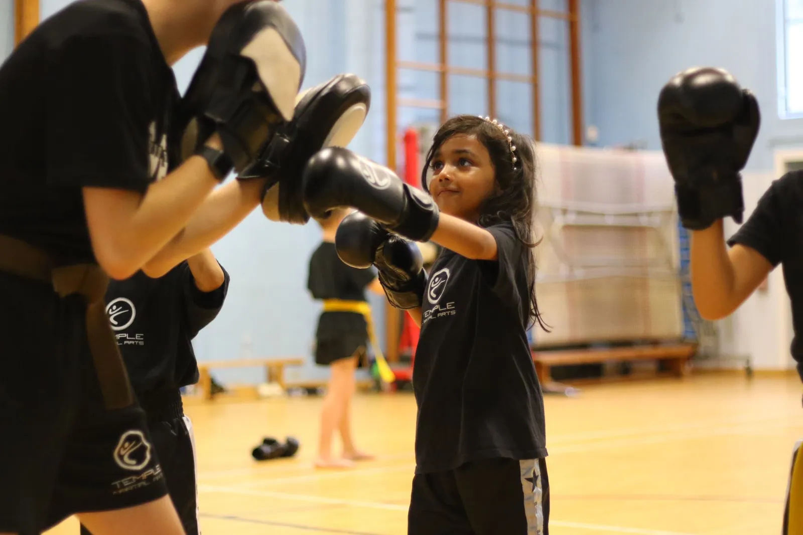 A young girl grinning as she punches a pad