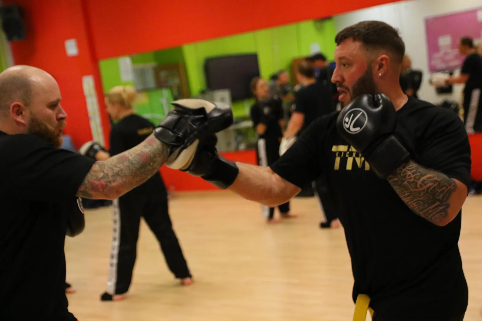 An adult member punching focus mitts held by a coach